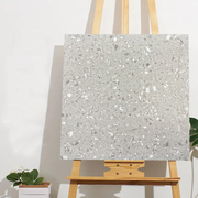 Tấm bảng màu xám có hoa văn đá cẩm thạch, đặt trên giá vẽ gỗ trước tường trắng.
