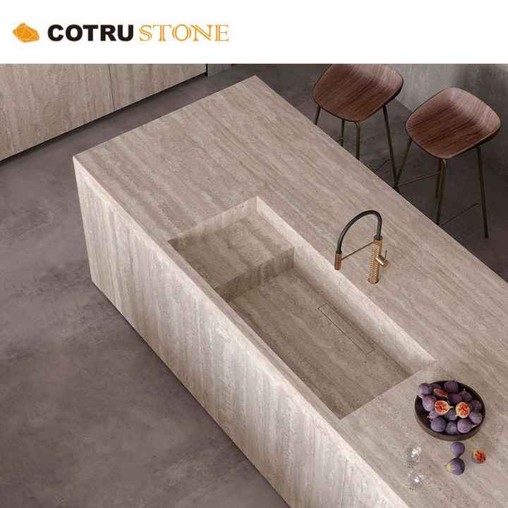 Chất liệu đá travertine màu kem, đảo bếp bằng đá tự nhiên, mặt bàn mài, thiết kế thoát nước vô hình phổ biến